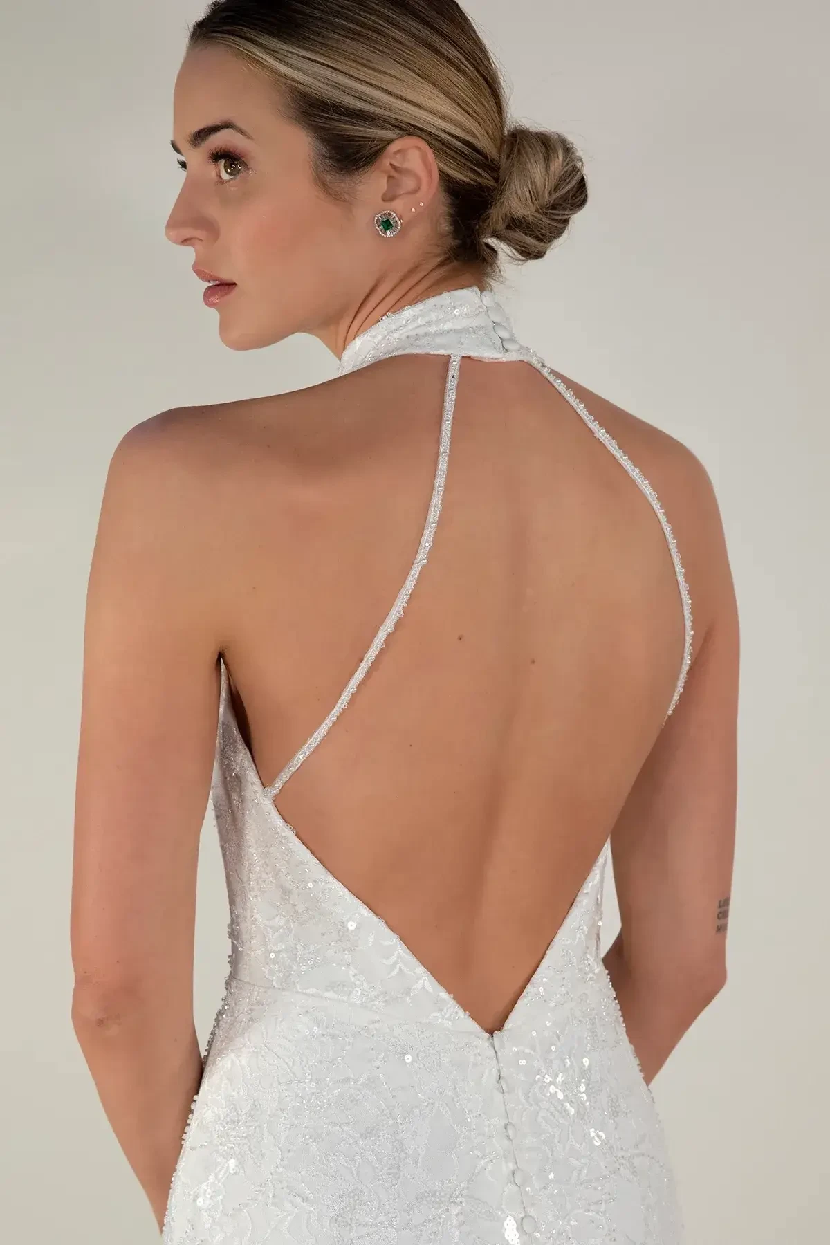 Model is wearing a halter style wedding dress with a low back and crisscross straps