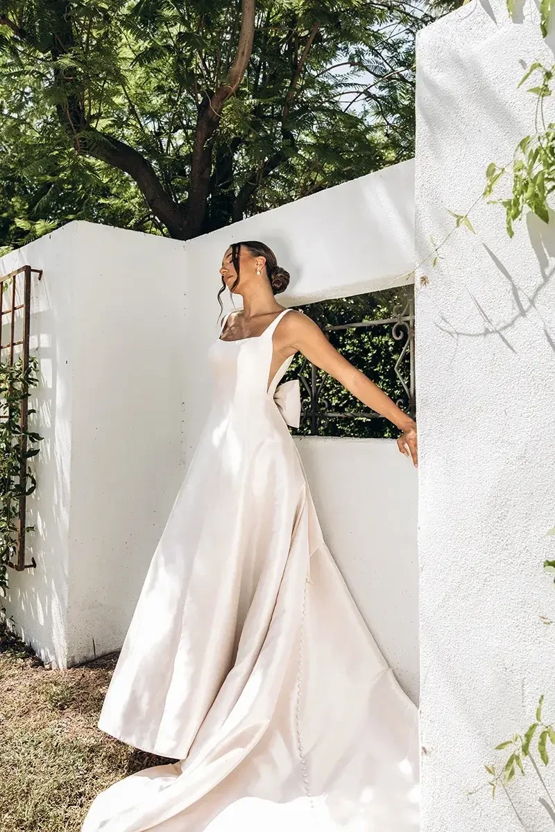Model is wearing a satin ball gown wedding dress with a square neckline