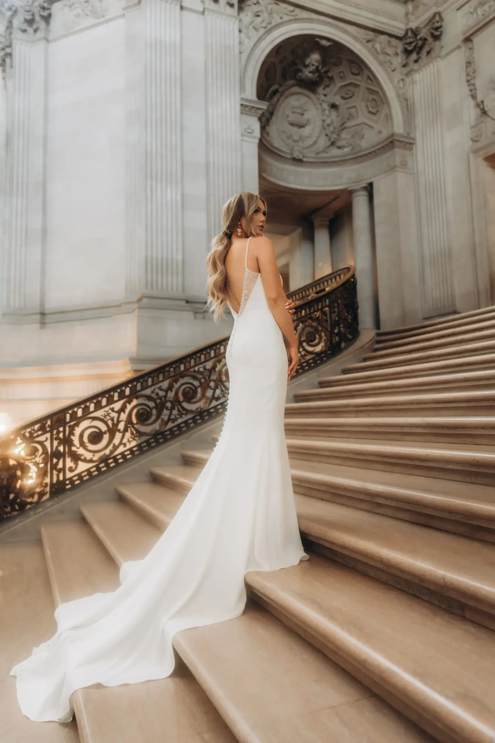 Model is wearing a glamorous wedding dress with a dramatic low back by stella york
