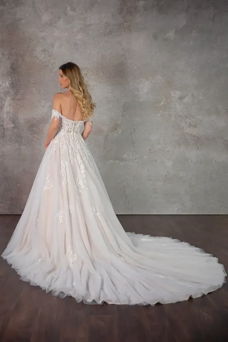 Model is wearing a dramatic ball gown with glitter tulle layers, floral lace appliqués, and detachable off-the-shoulder straps.