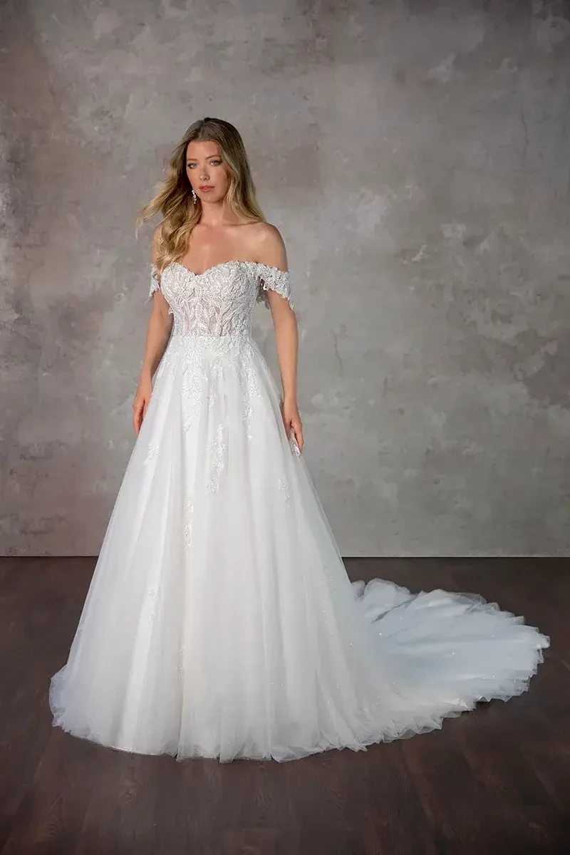 Model is wearing a dramatic ball gown with glitter tulle layers, floral lace appliqués, and detachable off-the-shoulder straps.